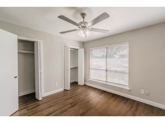 A room with a ceiling fan and wooden floors.