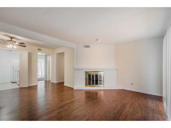 A large, empty room with a fireplace and wood flooring.