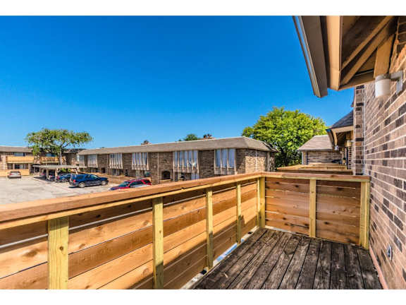 A wooden deck overlooks a parking lot and buildings.