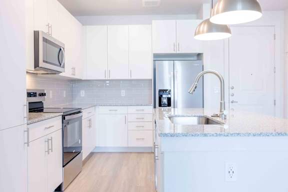 A modern kitchen with white cabinets and stainless steel appliances.