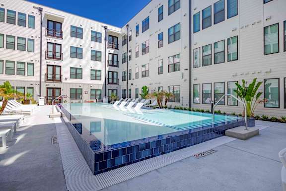 A swimming pool in front of a white building with a blue sky in the background.