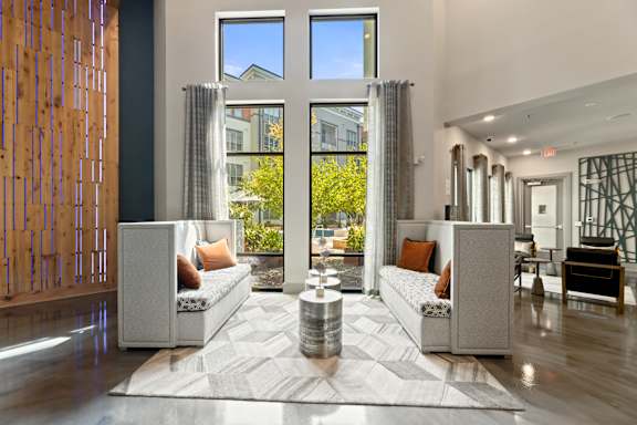A modern living room with a large window and a wooden partition on the left.