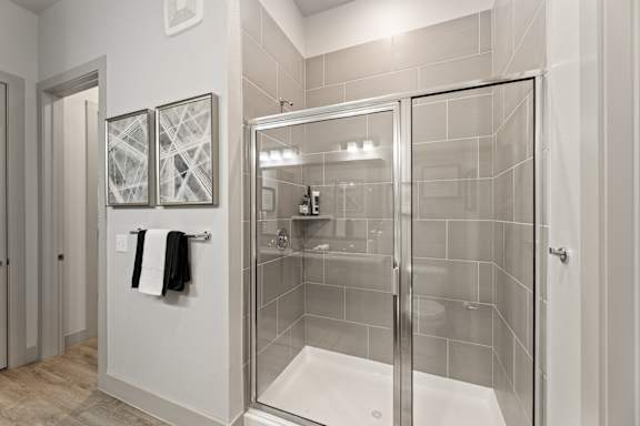 A bathroom with a walk-in shower and two towels hanging on the wall.