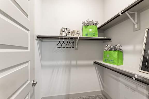 A white closet with two shelves and two green boxes on top.