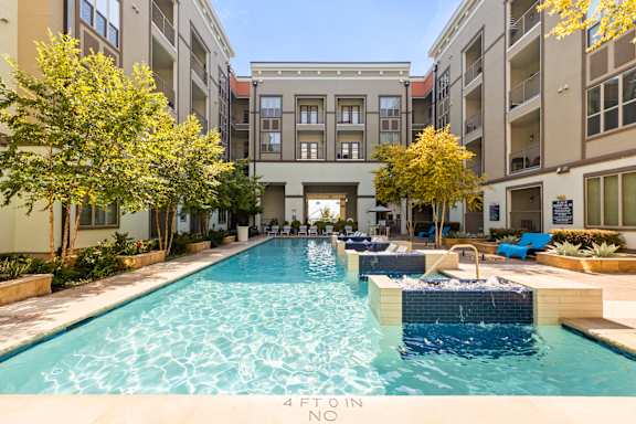 A swimming pool in a courtyard surrounded by trees and buildings.