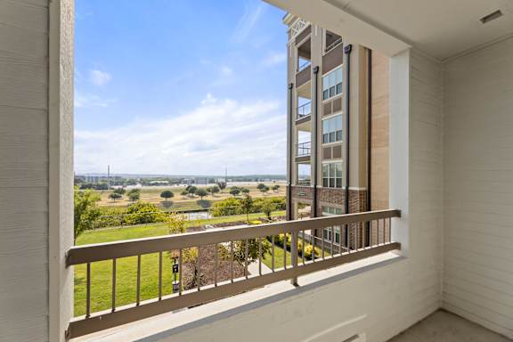A balcony with a view of a field and buildings.