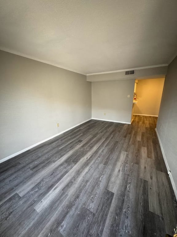 an empty living room with wood flooring