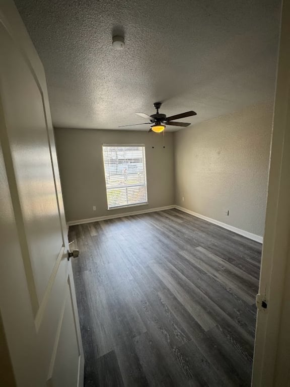 an empty room with a ceiling fan and wood floors