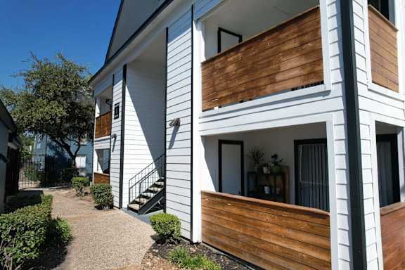 A white building with a brown wooden balcony.