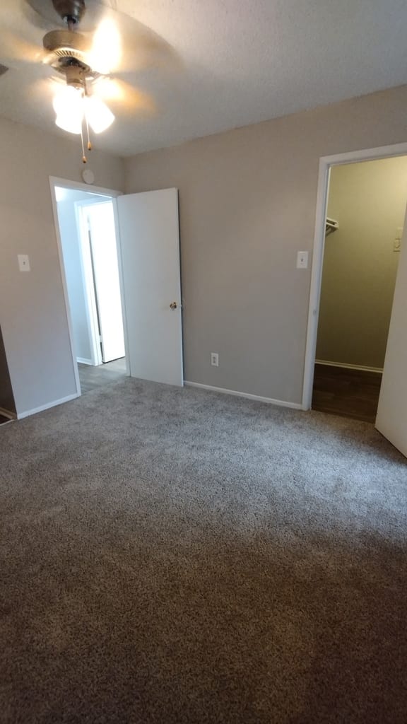 an empty living room with a carpeted floor and an open door to a bedroom