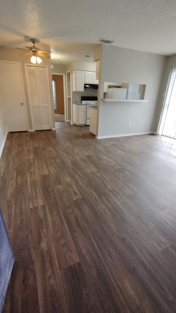 an empty living room and kitchen with wood floors