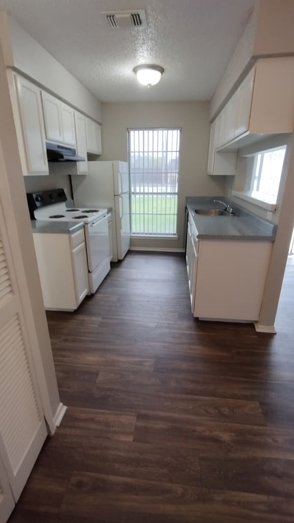 an empty kitchen with white cabinets and a wood floor