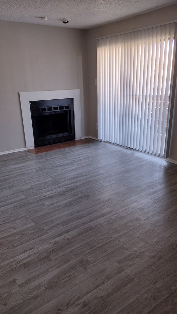 an empty living room with a fireplace and blinds