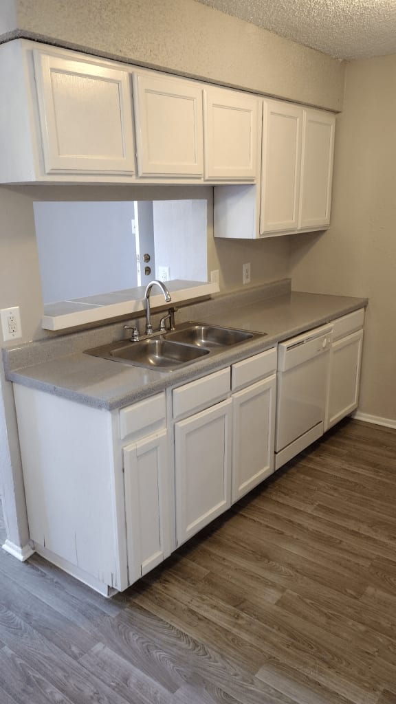 an empty kitchen with white cabinets and a sink