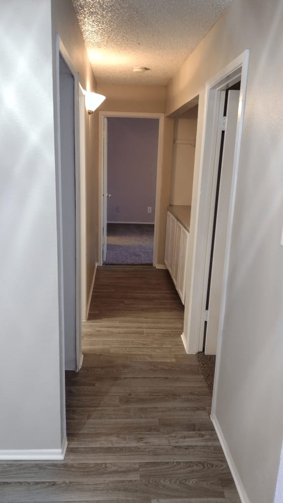 a look down the hallway of a home with wood floors and white walls