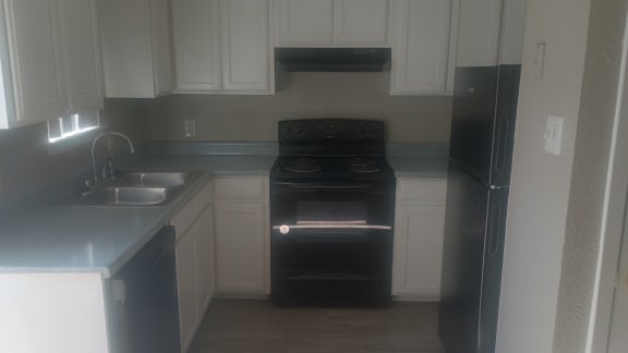 an empty kitchen with black appliances and white cabinets