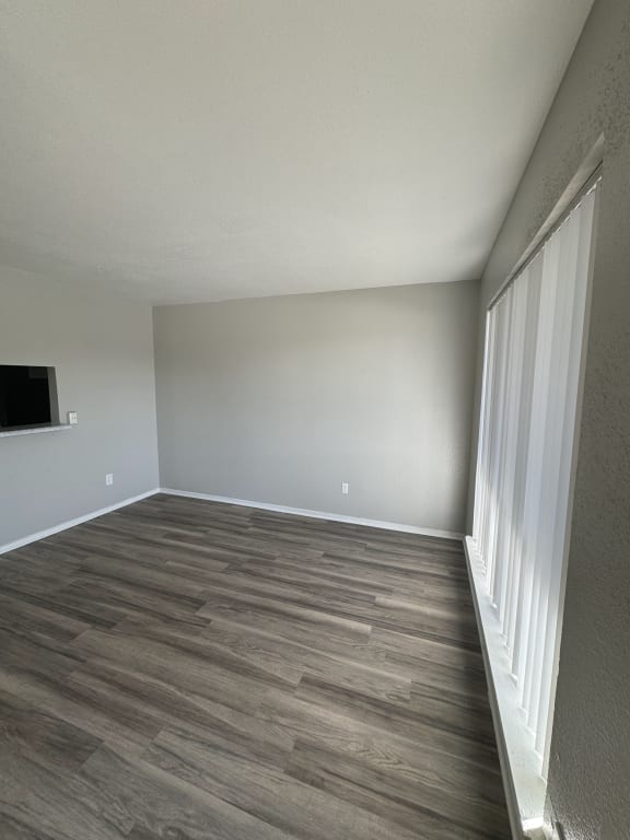 an empty living room with wood flooring and a window