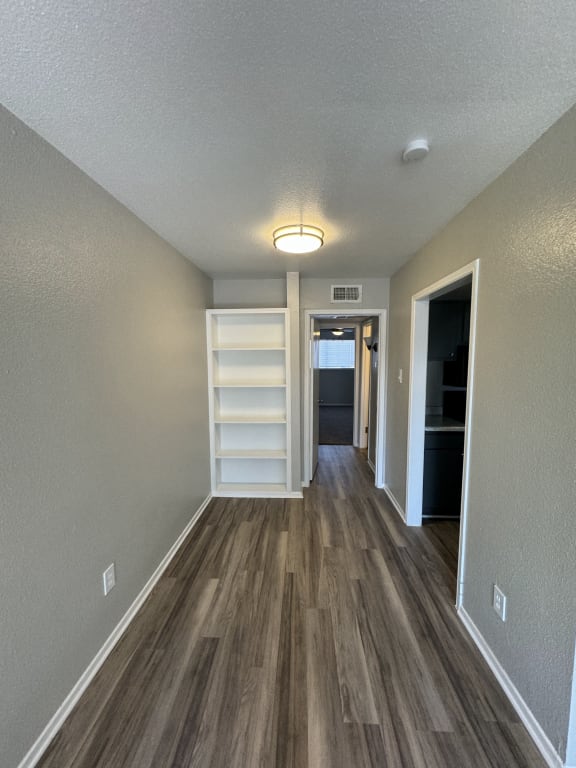 a hallway with wood flooring and a closet with shelves