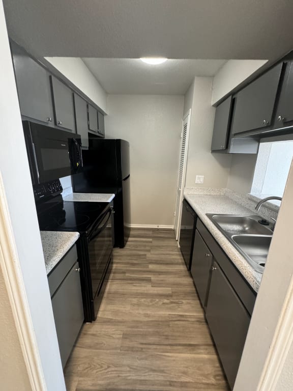 a kitchen with black and stainless steel appliances and a wood floor