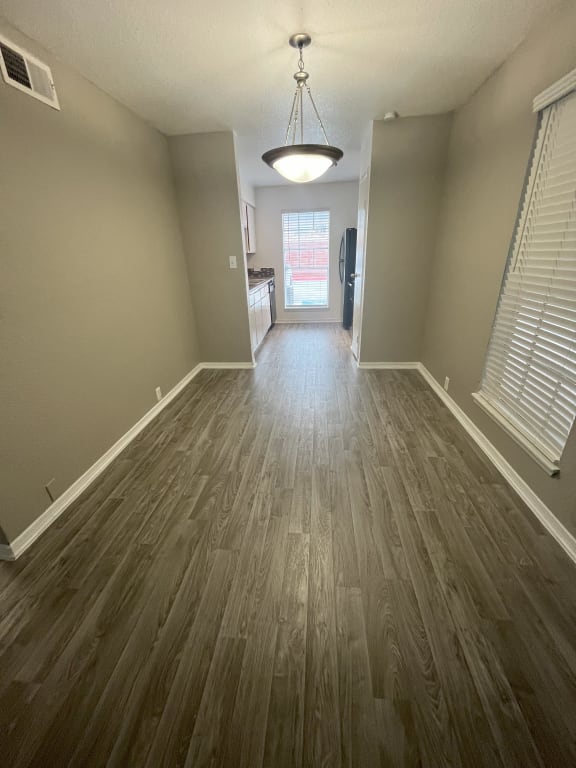 an empty living room with wood floors and a window