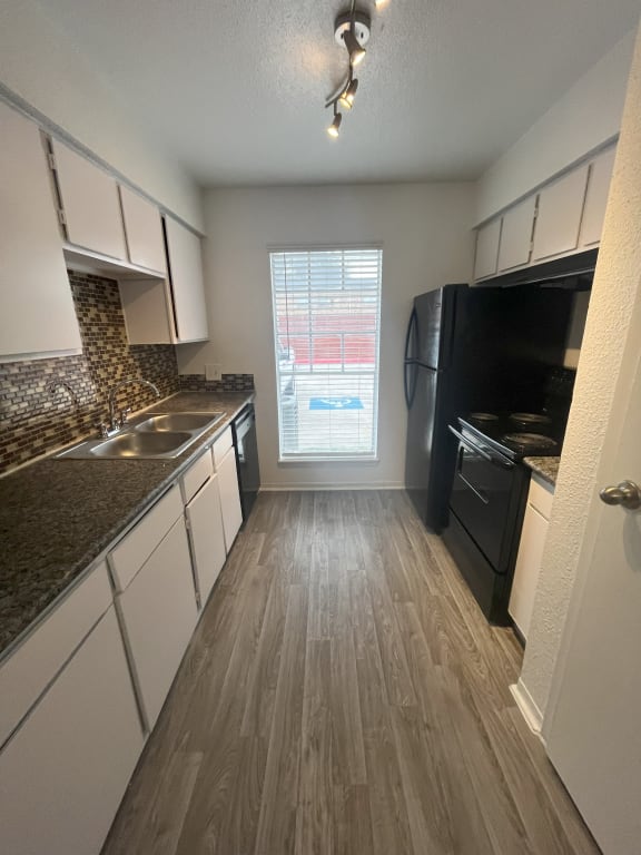 an empty kitchen with white cabinets and black appliances