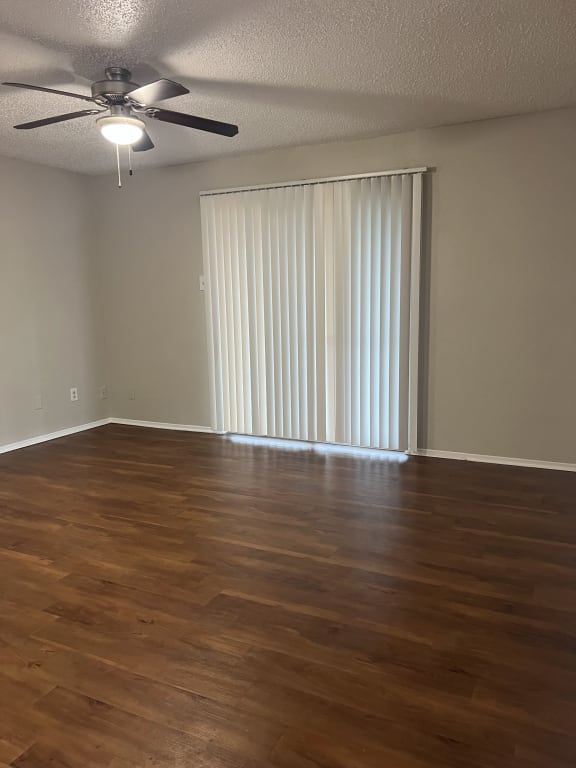 an empty living room with wood floors and a sliding glass door