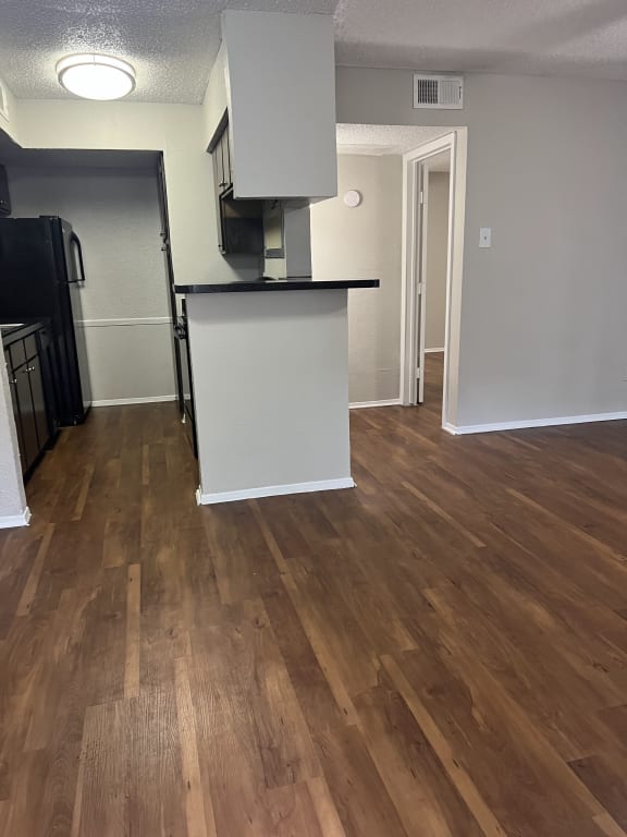 an open kitchen and living room with hardwood floors and a kitchen island with a
