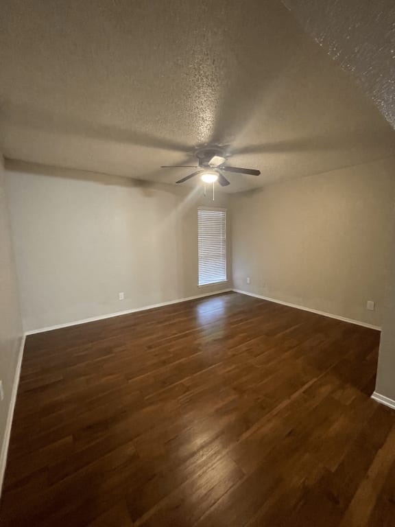 an empty living room with wood floors and a ceiling fan