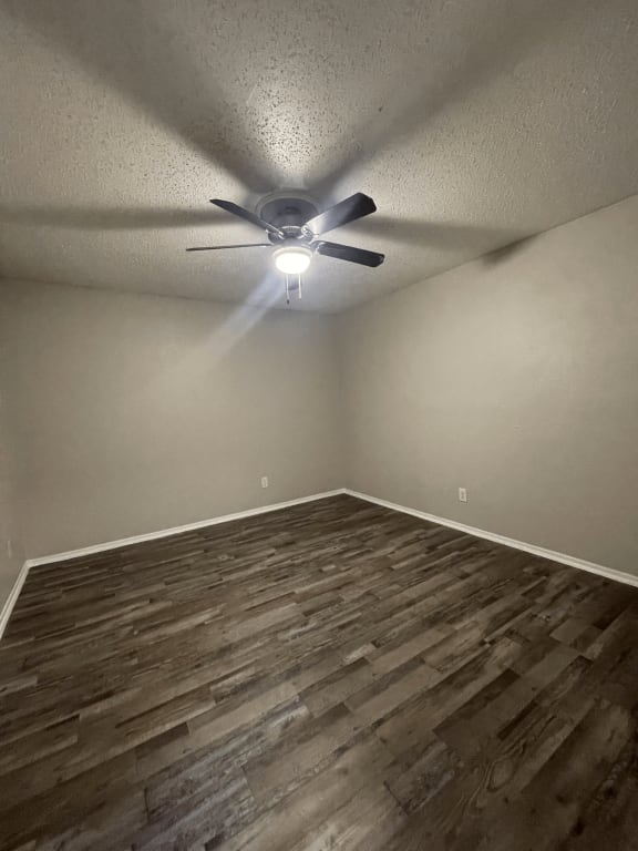 an empty living room with wood flooring and a ceiling fan