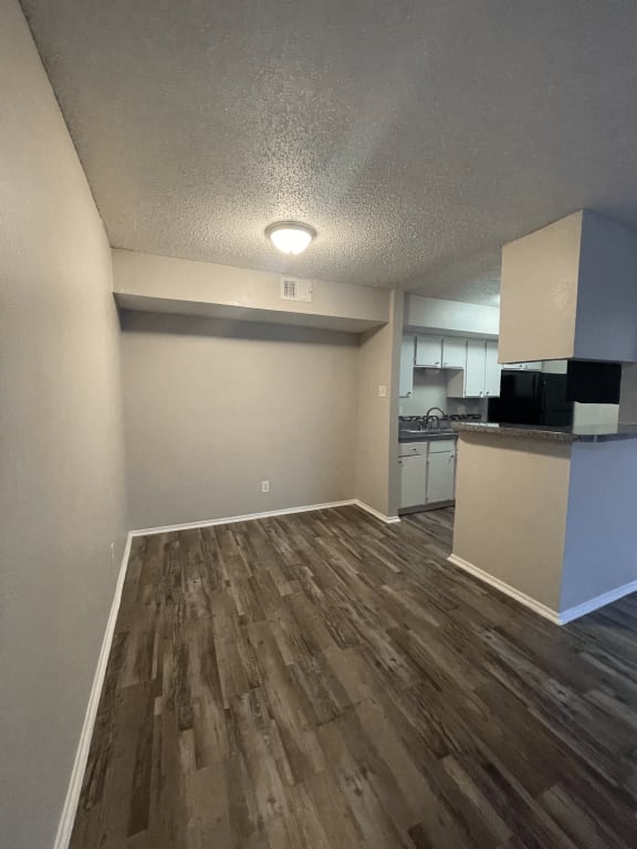 an empty living room and kitchen with wood flooring