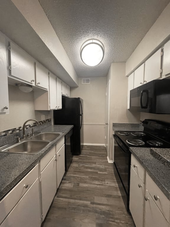an empty kitchen with granite counter tops and white cabinets