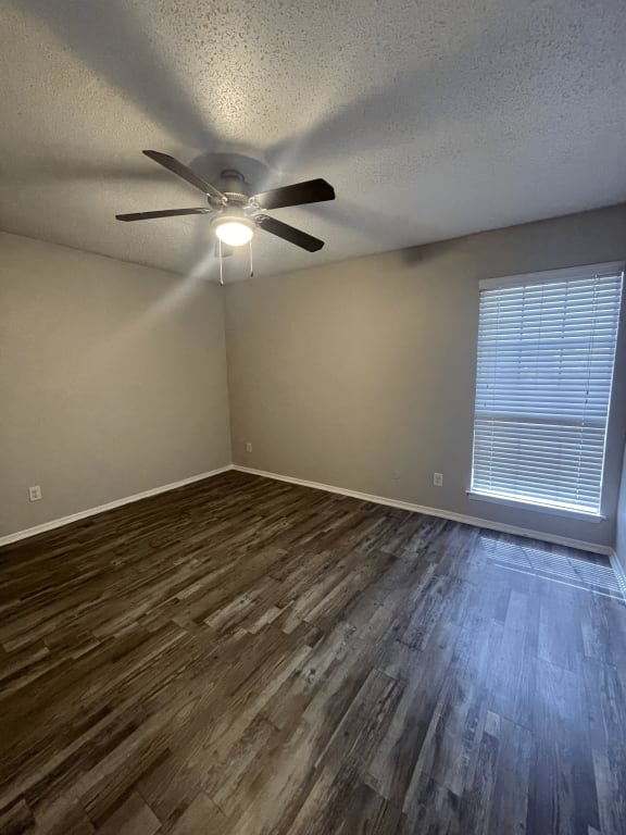 an empty living room with wood floors and a ceiling fan