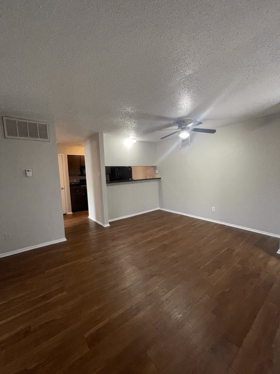 an empty living room with wood floors and a ceiling fan