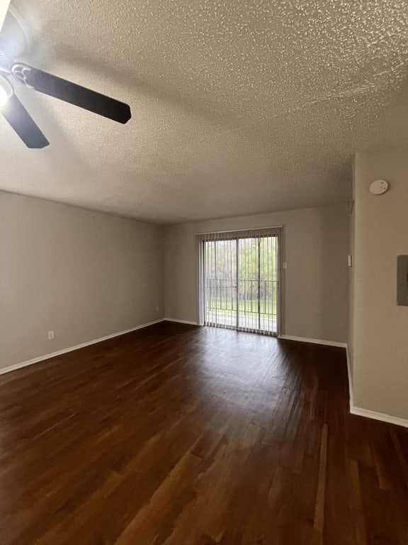 an empty living room with wood floors and a sliding glass door