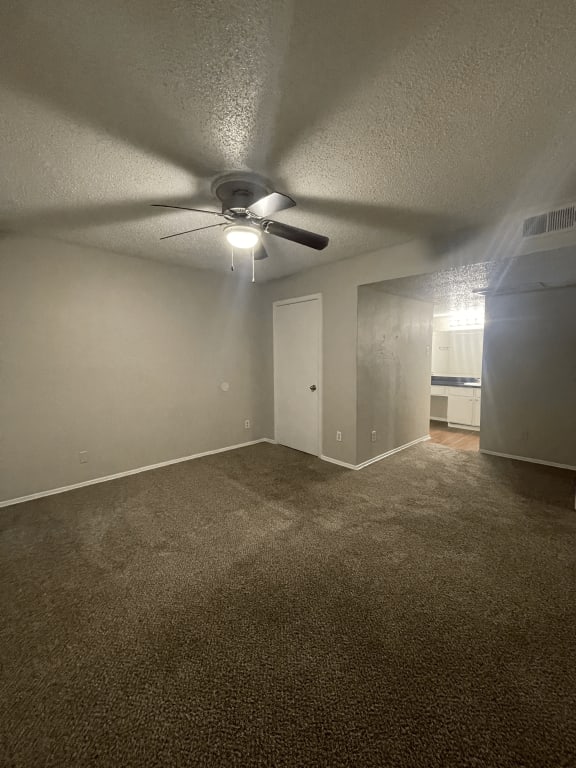 an empty living room with a ceiling fan