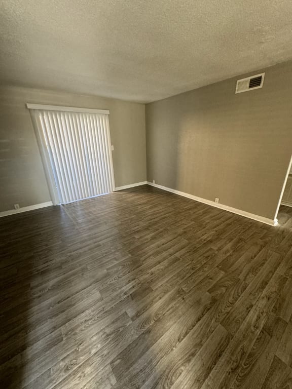 an empty living room with wood floors and a window