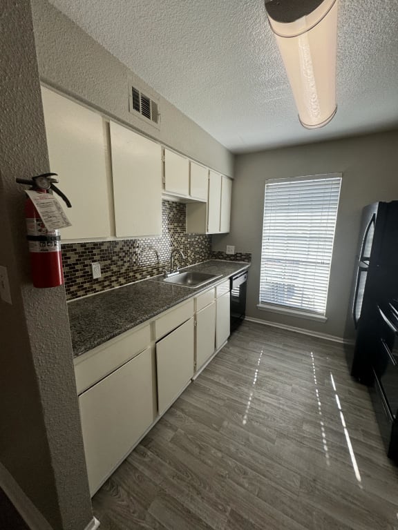 a kitchen with white cabinets and a sink and a window