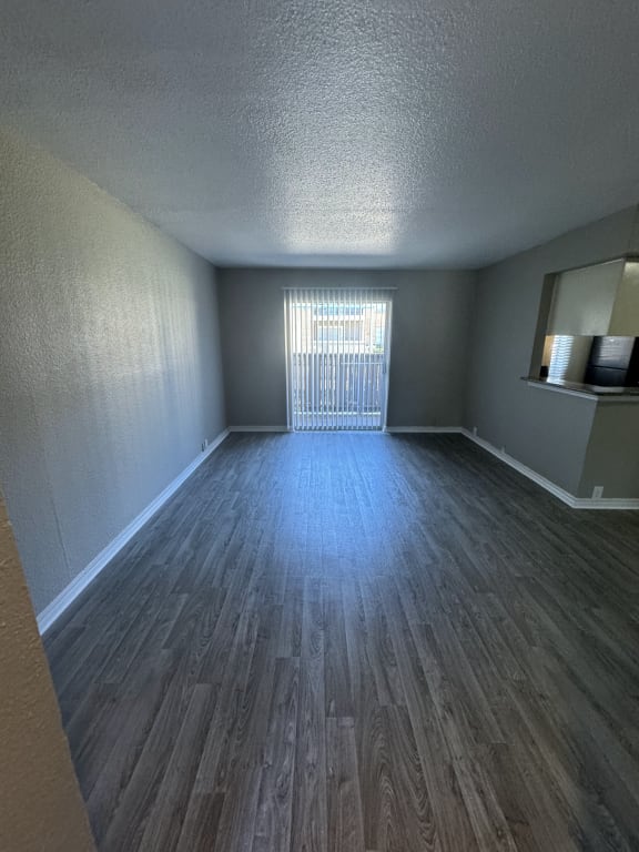 an empty living room with wood flooring and a window
