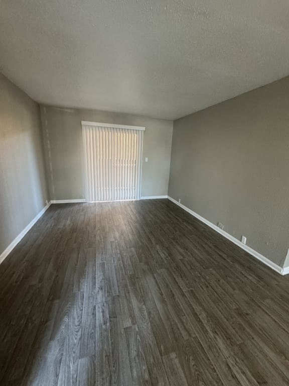 an empty living room with wood flooring and a window