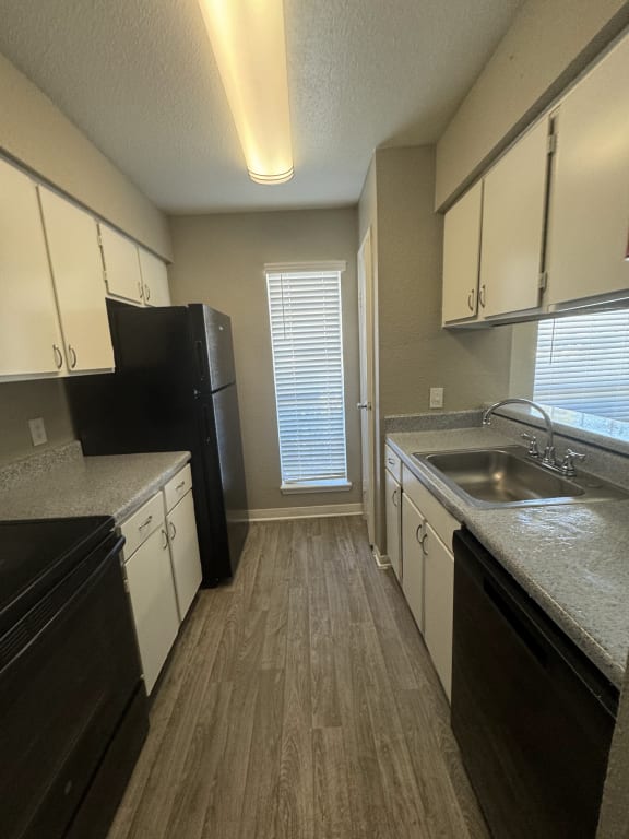a kitchen with white cabinets and a sink and a black refrigerator