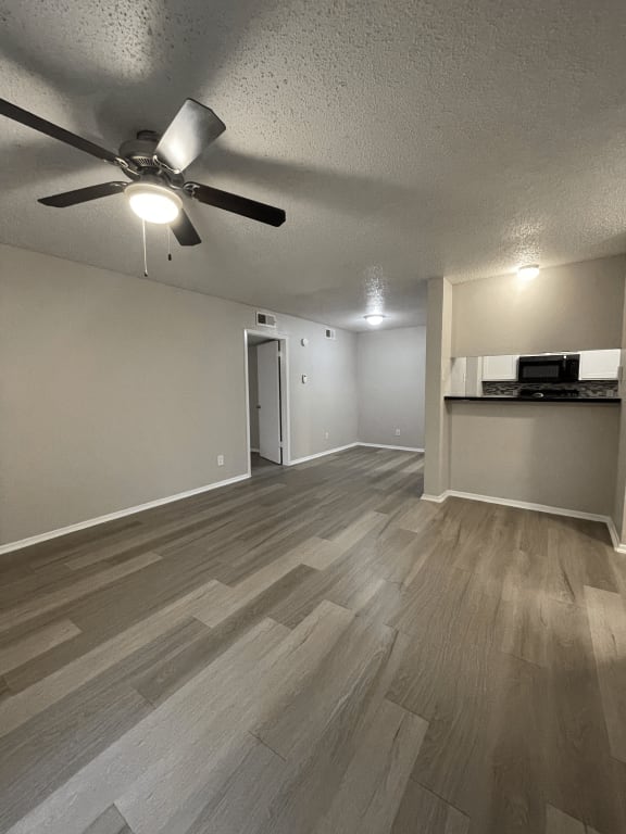an empty living room with wood floors and a ceiling fan