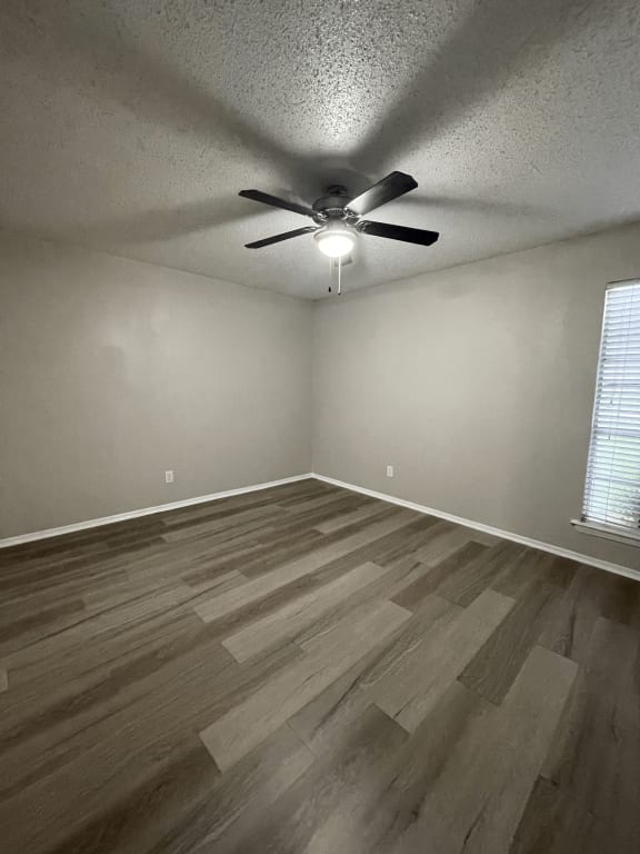 an empty living room with hardwood floors and a ceiling fan