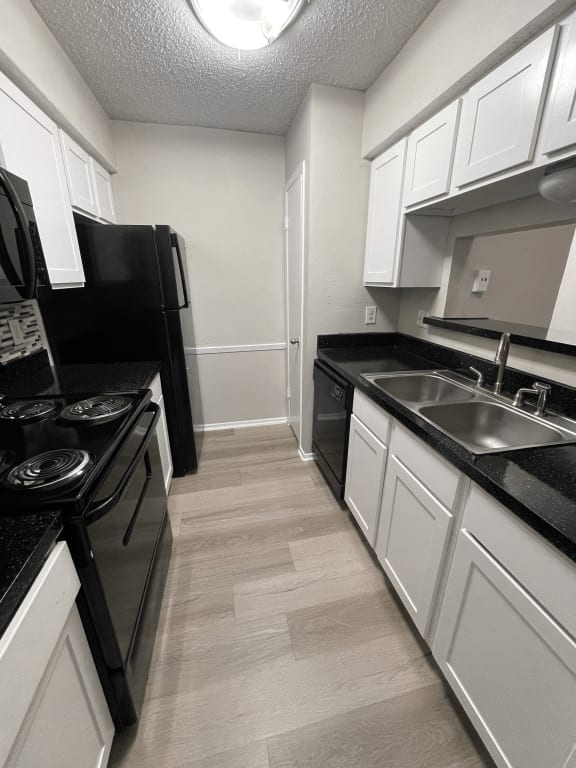 a kitchen with white cabinets and black appliances and a sink