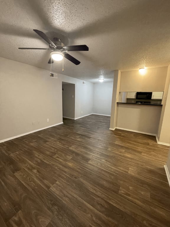 an empty living room with wood floors and a ceiling fan