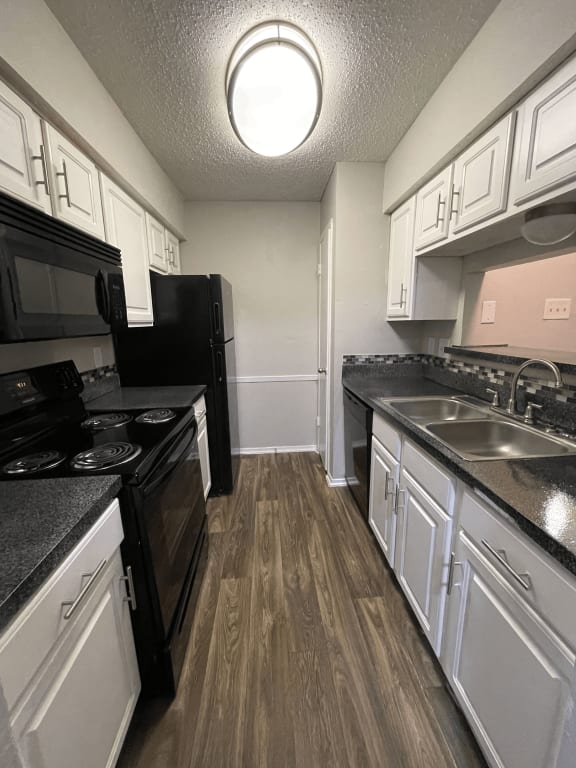 a kitchen with white cabinets and black appliances and a sink
