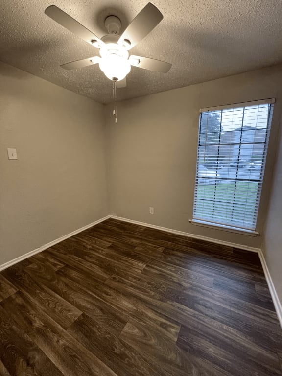 an empty bedroom with a ceiling fan and a window