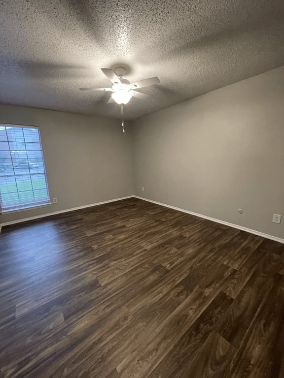 an empty living room with wood floors and a ceiling fan