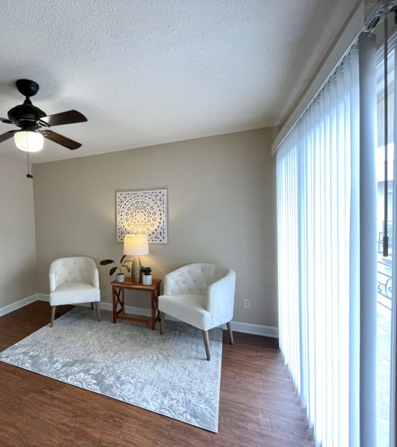 a living room with two chairs and a table and a ceiling fan