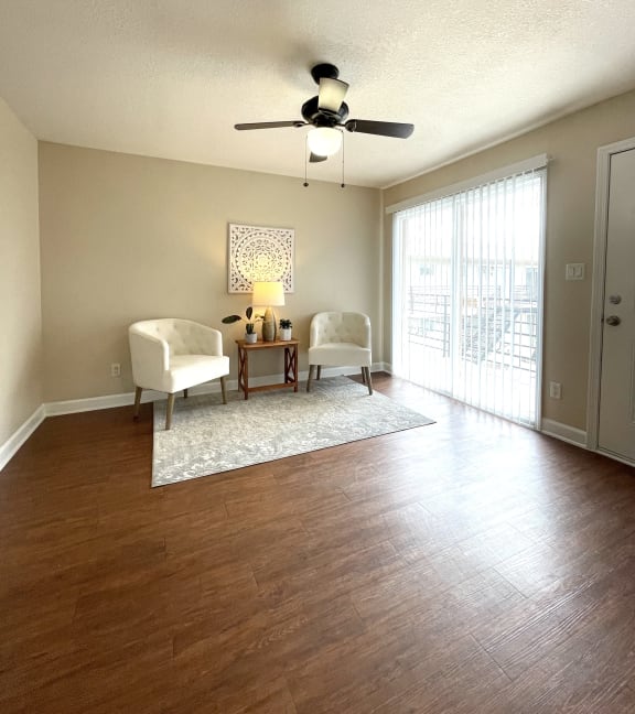 an empty living room with a ceiling fan and a window