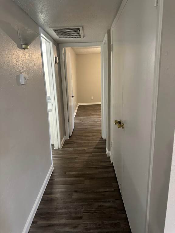 a hallway with wood floors and white walls and a door